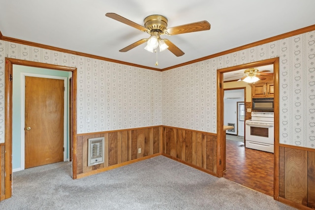 carpeted empty room featuring heating unit, ornamental molding, and ceiling fan