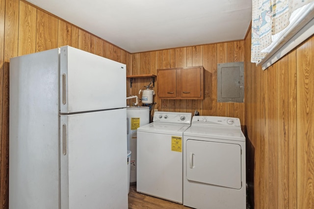 washroom featuring washer and dryer, wooden walls, water heater, cabinets, and electric panel