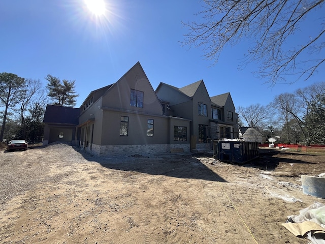 view of side of property featuring a garage, stone siding, driveway, and stucco siding