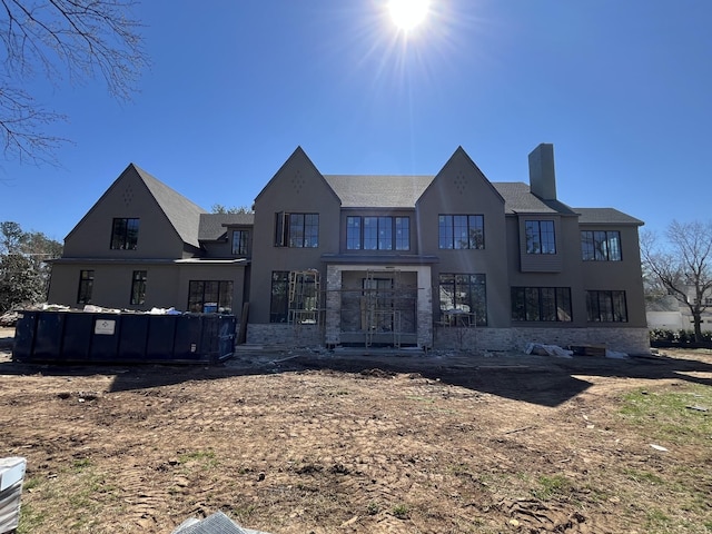 rear view of property with a chimney and stucco siding