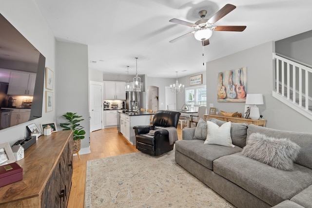 living room featuring ceiling fan with notable chandelier and light hardwood / wood-style floors