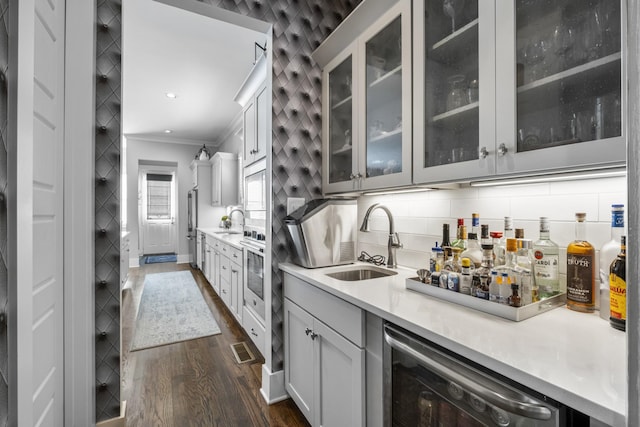 kitchen with ornamental molding, dark hardwood / wood-style floors, sink, and decorative backsplash