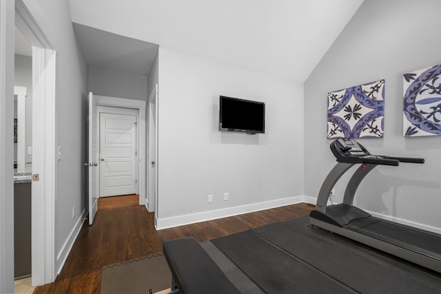 exercise room featuring dark wood-type flooring and vaulted ceiling