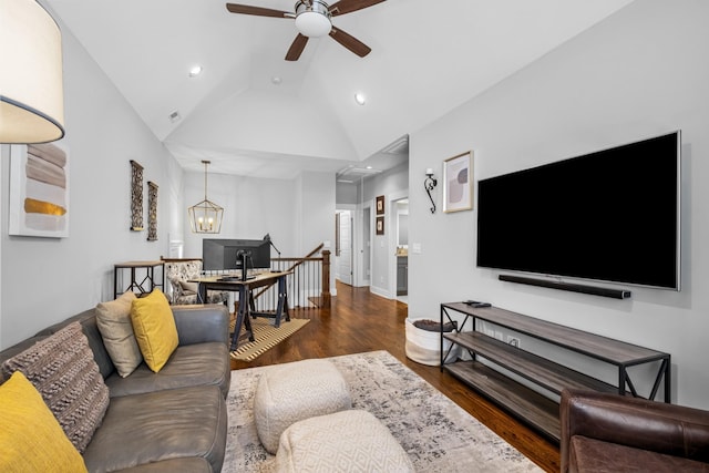 living room featuring ceiling fan with notable chandelier, dark hardwood / wood-style floors, and vaulted ceiling