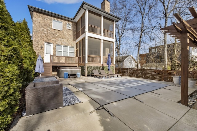 rear view of property featuring a hot tub, a patio, and a sunroom