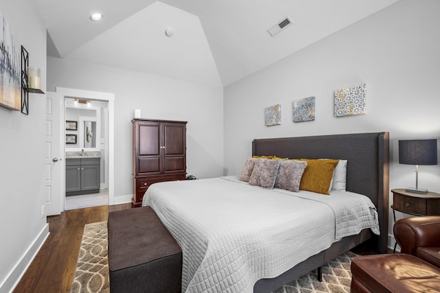 bedroom with dark hardwood / wood-style flooring, vaulted ceiling, and ensuite bathroom