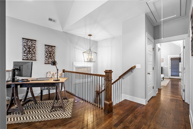 hall featuring dark wood-type flooring, lofted ceiling, and an inviting chandelier