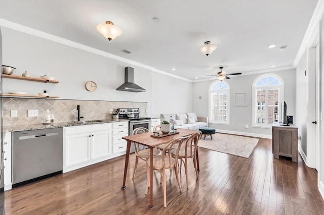 kitchen with tasteful backsplash, white cabinetry, stainless steel appliances, light stone countertops, and wall chimney exhaust hood