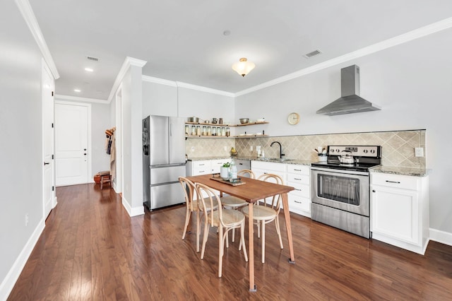 kitchen featuring white cabinetry, light stone counters, appliances with stainless steel finishes, decorative backsplash, and wall chimney range hood