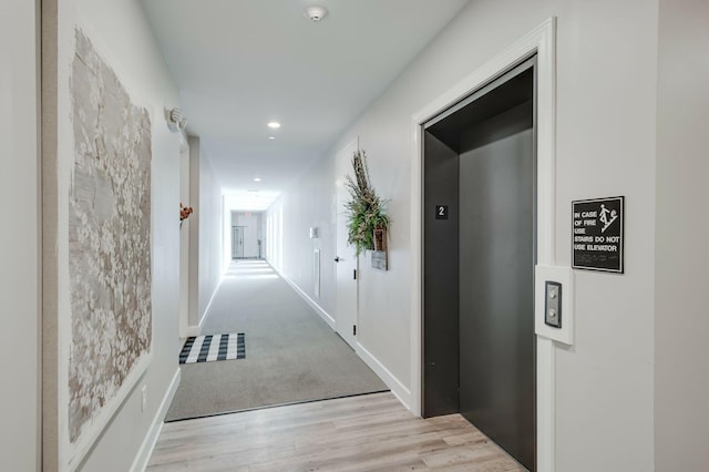 hall with elevator and light wood-type flooring