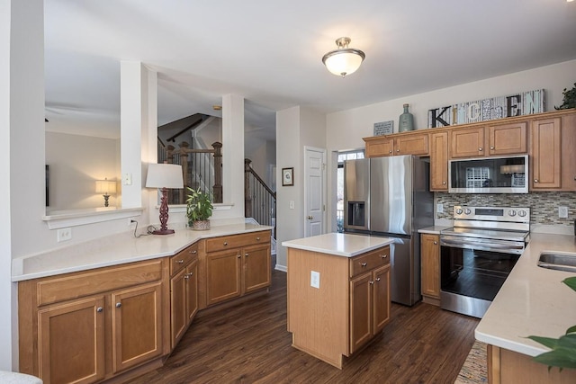 kitchen with dark wood-type flooring, decorative backsplash, appliances with stainless steel finishes, and a kitchen island