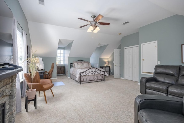 carpeted bedroom featuring lofted ceiling, a stone fireplace, and ceiling fan