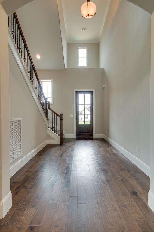 foyer featuring crown molding, dark wood-type flooring, and a high ceiling