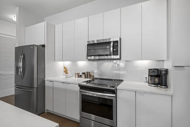 kitchen featuring appliances with stainless steel finishes, dark wood-type flooring, and white cabinets