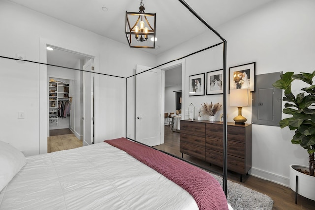 bedroom featuring wood-type flooring, electric panel, a closet, and a notable chandelier