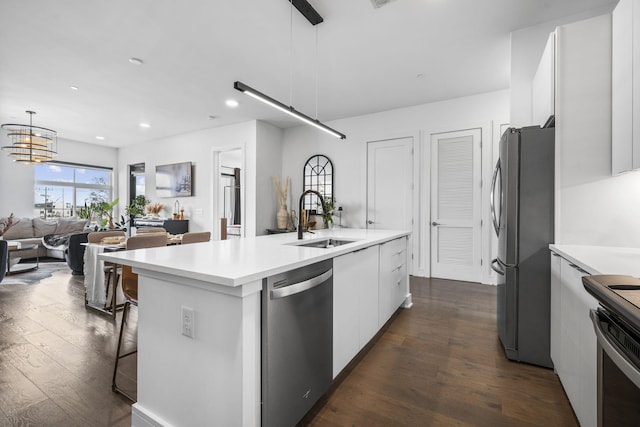 kitchen featuring sink, white cabinetry, a kitchen island with sink, stainless steel appliances, and decorative light fixtures