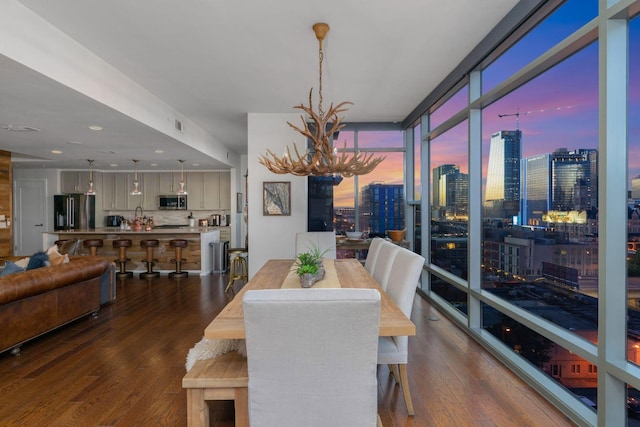 dining area featuring a notable chandelier, dark wood-type flooring, and floor to ceiling windows