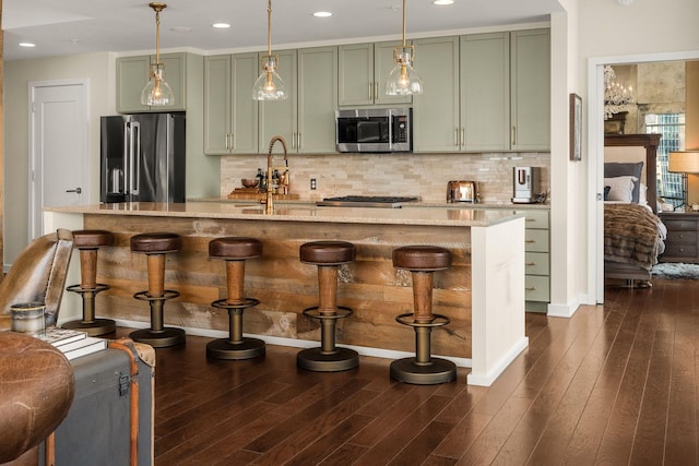 kitchen with stainless steel appliances, green cabinets, and light stone counters