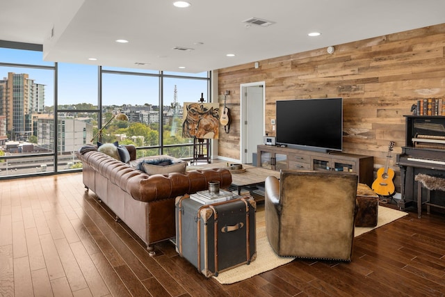 living room with dark wood-type flooring, a healthy amount of sunlight, floor to ceiling windows, and wood walls