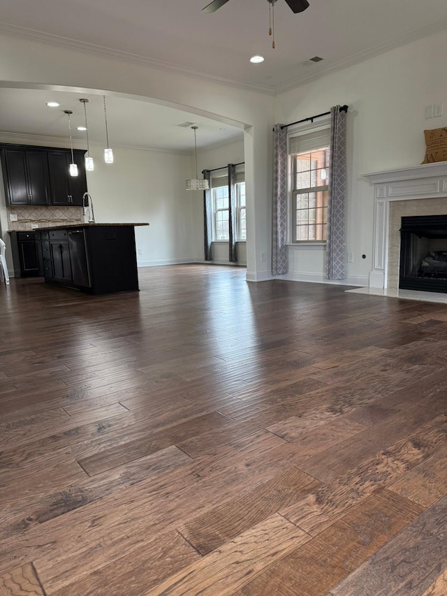 unfurnished living room with crown molding, dark wood-type flooring, sink, and ceiling fan