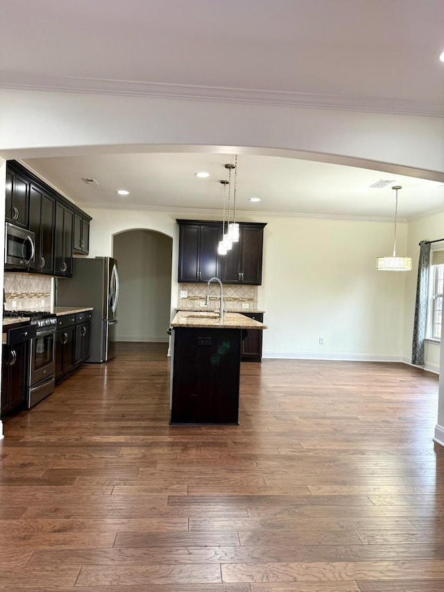 kitchen featuring an island with sink, appliances with stainless steel finishes, dark hardwood / wood-style floors, and decorative light fixtures