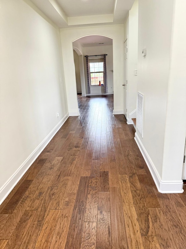 hallway featuring a tray ceiling and dark hardwood / wood-style floors