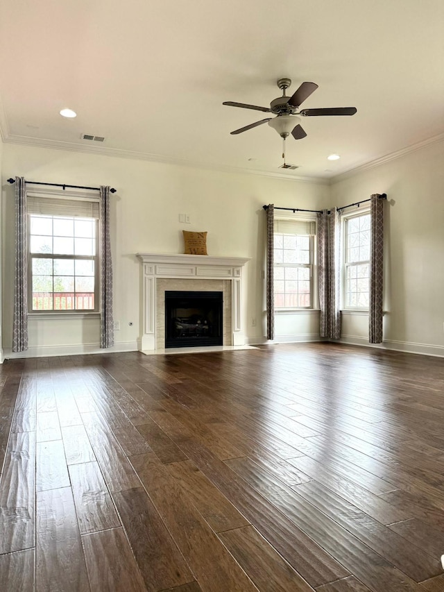 unfurnished living room featuring crown molding, ceiling fan, dark wood-type flooring, and a tile fireplace