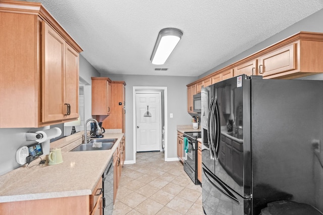 kitchen featuring sink, light tile patterned floors, black appliances, and a textured ceiling