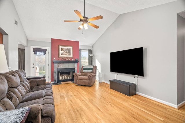 living room featuring lofted ceiling, hardwood / wood-style flooring, a fireplace, and ceiling fan