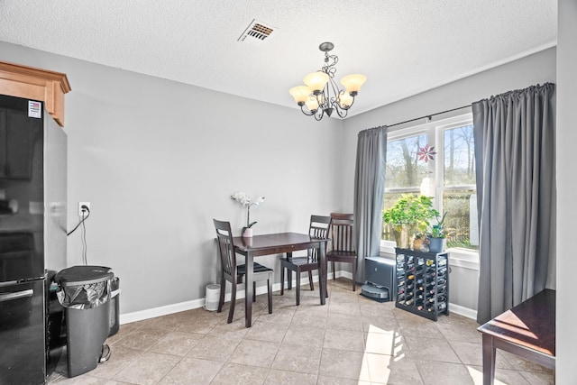 tiled dining room with a notable chandelier and a textured ceiling