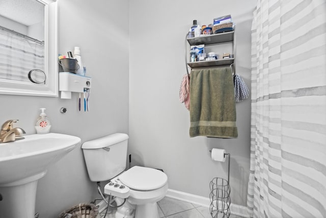 bathroom with tile patterned floors, toilet, sink, a textured ceiling, and curtained shower