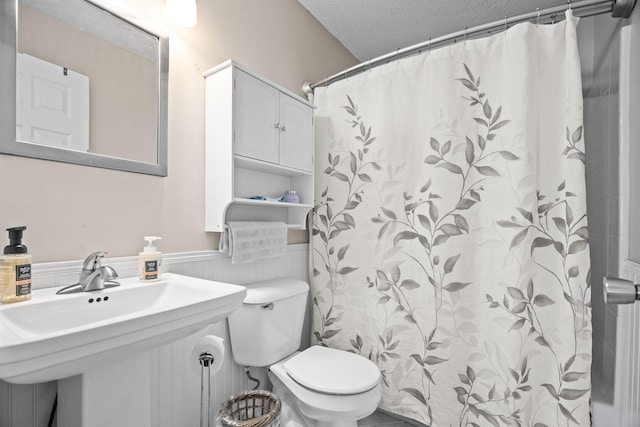 bathroom with a shower with curtain, toilet, sink, and a textured ceiling