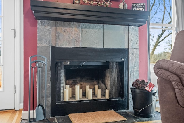 interior details with wood-type flooring and a tile fireplace