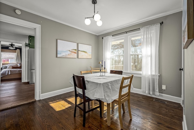 dining area featuring dark wood-type flooring, ornamental molding, and a chandelier