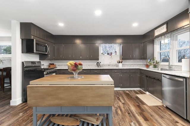 kitchen featuring dark wood-type flooring, sink, dark brown cabinets, stainless steel appliances, and decorative backsplash