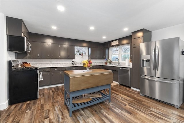 kitchen featuring sink, decorative backsplash, dark wood-type flooring, stainless steel appliances, and dark brown cabinets