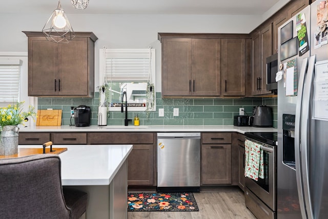 kitchen with pendant lighting, sink, decorative backsplash, dark brown cabinetry, and stainless steel appliances