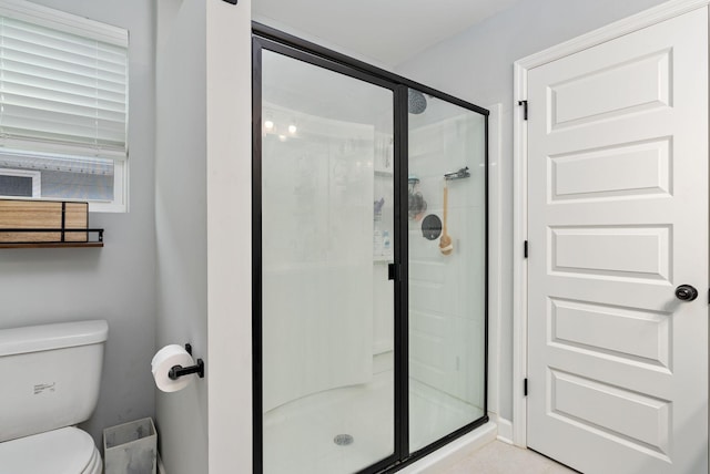 bathroom featuring a shower with door and toilet