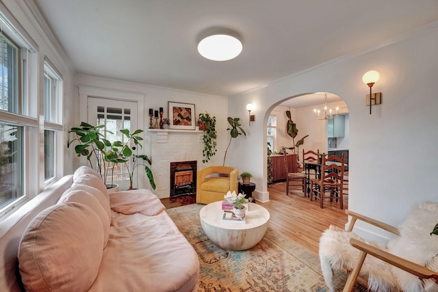 living room featuring hardwood / wood-style flooring, crown molding, and a brick fireplace