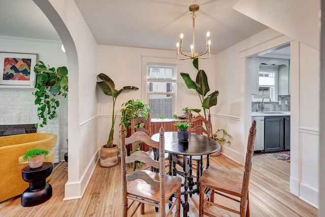 dining space with sink, a notable chandelier, and light hardwood / wood-style flooring