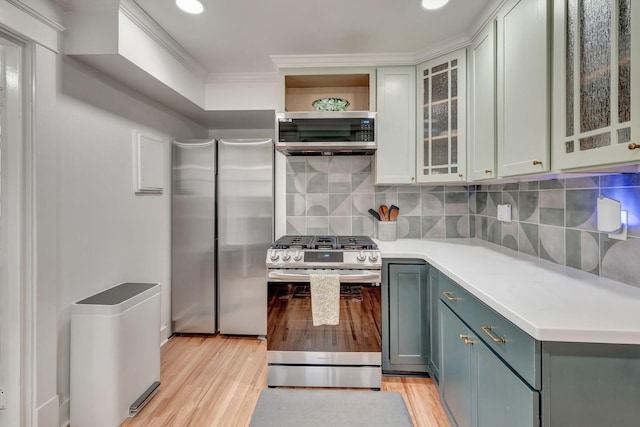 kitchen with tasteful backsplash, appliances with stainless steel finishes, crown molding, and light hardwood / wood-style flooring