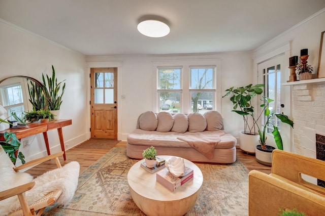 living room with hardwood / wood-style flooring, ornamental molding, and a brick fireplace