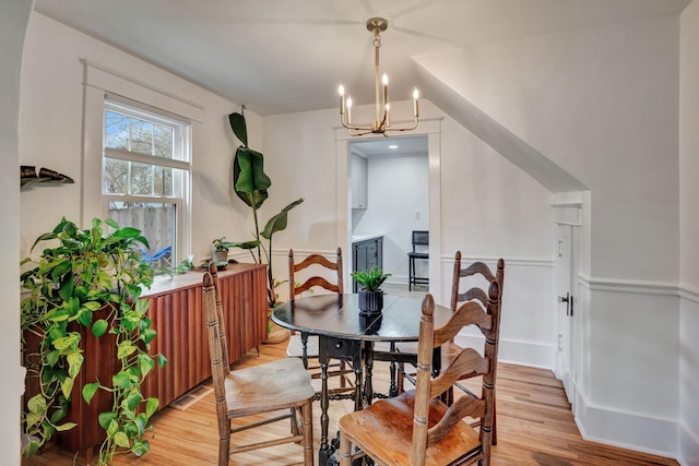 dining area featuring vaulted ceiling, a chandelier, and light wood-type flooring