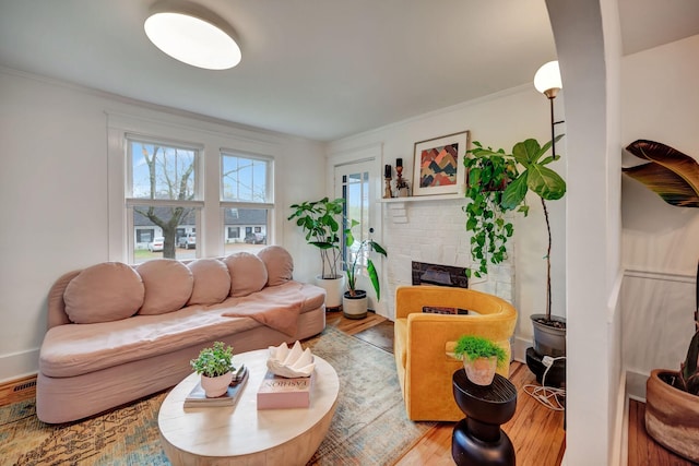 living room featuring crown molding, wood-type flooring, and a fireplace