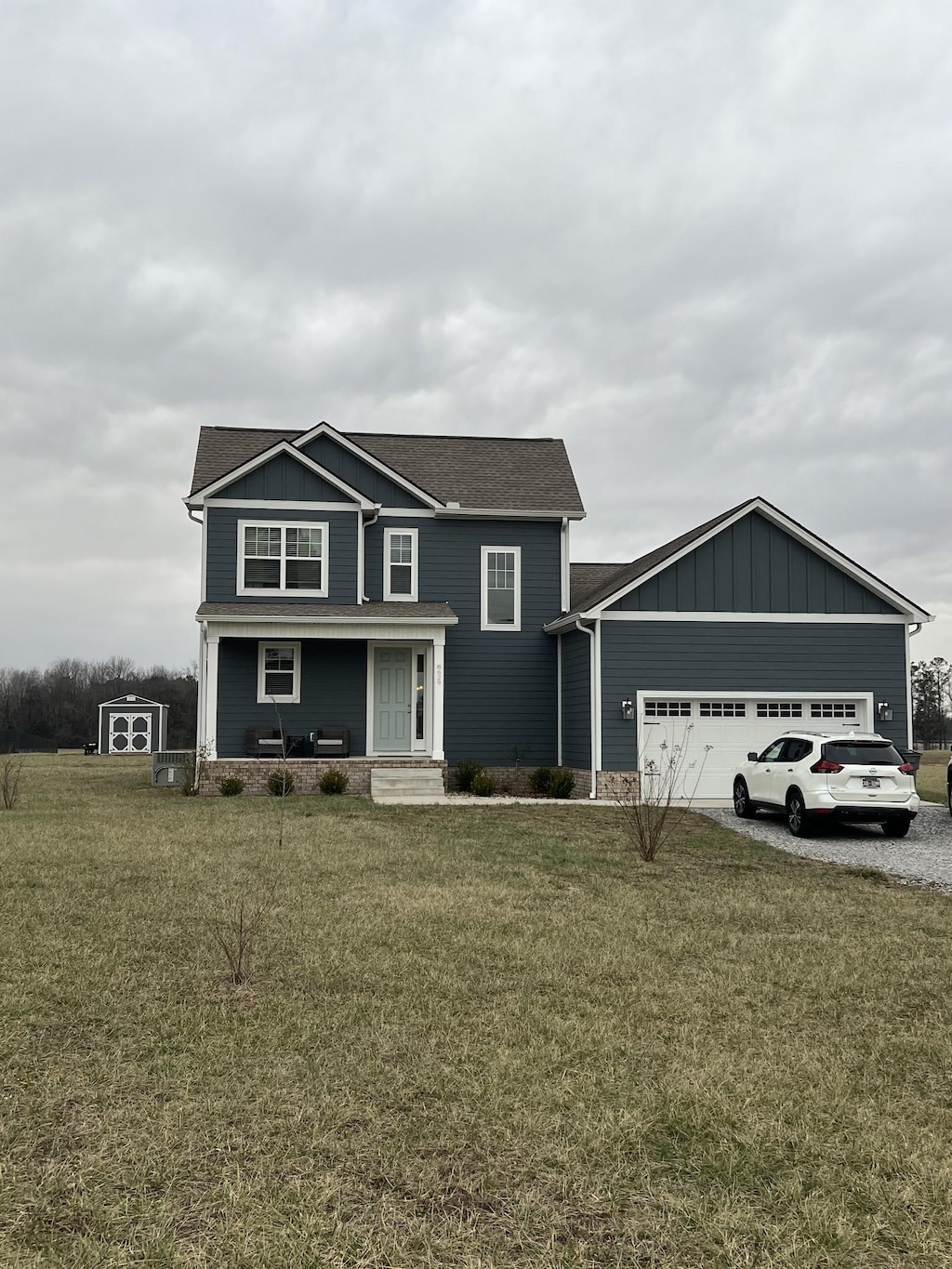 view of front of property featuring a porch, a garage, and a front yard