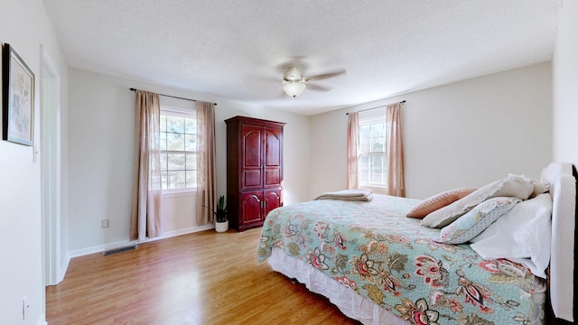 bedroom featuring ceiling fan, a textured ceiling, and light wood-type flooring