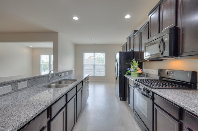 kitchen with pendant lighting, sink, dark brown cabinetry, black appliances, and light stone countertops