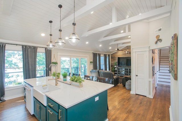 kitchen featuring an island with sink, plenty of natural light, and vaulted ceiling with beams