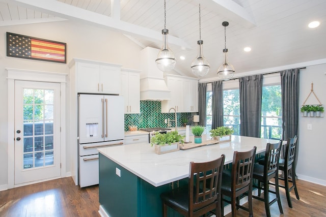 kitchen with pendant lighting, white cabinetry, high end white refrigerator, a kitchen breakfast bar, and a spacious island