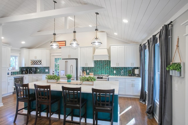 kitchen featuring white cabinetry, a kitchen island with sink, white appliances, and decorative light fixtures